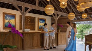 A reception area with wooden beams, hanging wicker lamps, and framed artwork on the walls.