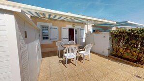 A patio with a table and chairs, a covered area, and a wall with a door. - Le Lagon Bleu (Bretignolles-sur-Mer)