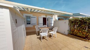 A patio with a table and chairs, a covered area, and a wall with a door.