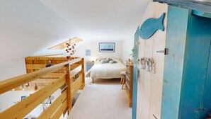 A bedroom with a bunk bed, a bed with patterned pillows, a blue wardrobe, and a sailboat painting on the wall. - Le Lagon Bleu (Bretignolles-sur-Mer)