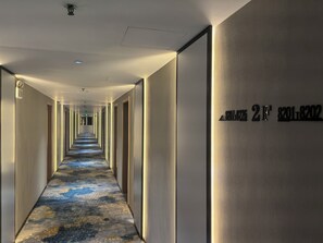 A hotel hallway with a carpeted floor, doors on both sides, and a sign indicating room numbers 2F and 2G. - Baolong Homelike Hotel Zhongshan Branch (Shanghai)