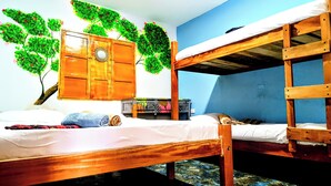 Camera con letto a castello, un'armadietto in legno, un tavolino e una parete decorata con motivi vegetali.