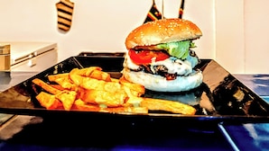 Un hamburger e patatine fritte su un vassoio nero.