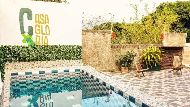 Una piscina con motivo a scacchi, circondata da un muro in pietra e piante in vaso.