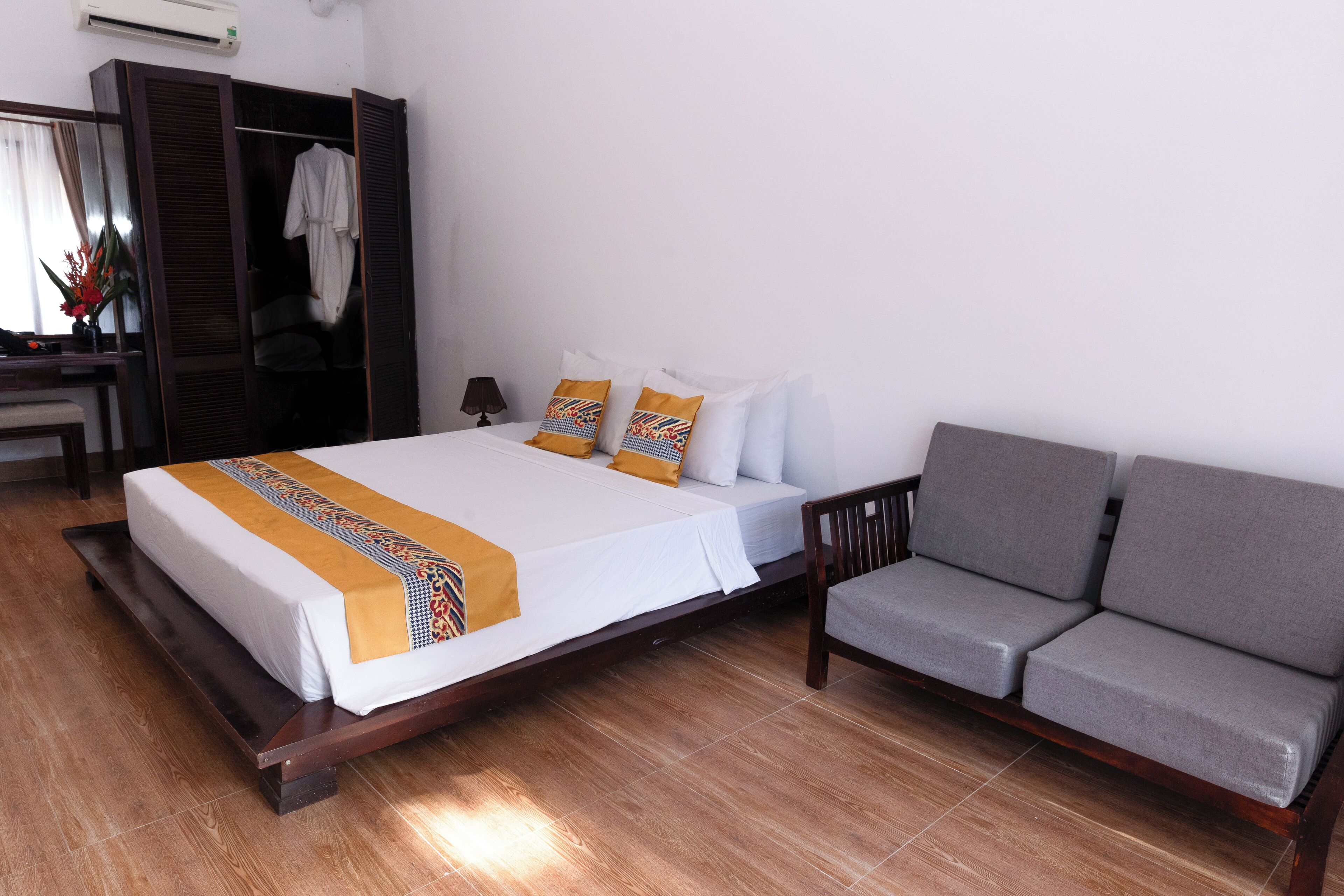 A hotel room with a bed, a sofa, a wardrobe, and a desk.