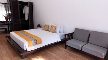 A hotel room with a bed, a sofa, a wardrobe, and a desk.