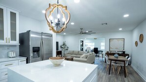 A modern kitchen with a large island, stainless steel appliances, and a chandelier.