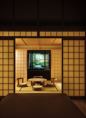 Een traditionele Japanse kamer met tatami vloerbedekking, een lage tafel en een groot raam met uitzicht op een tuin.