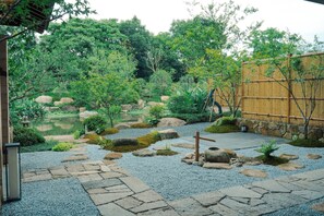 A traditional Japanese garden with a koi pond, stone pathways, and bamboo fencing. - HARUNOYA (Hangzhou)