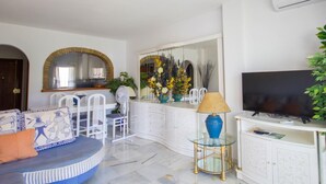 A living room with a sofa, chairs, a TV, a glass table, and a cabinet. - Erisa 2, 28 - Terrace, Swimming Pool, Parking, Second line of beach. 2 bedrooms (Torremolinos)