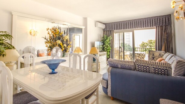 A modern living room with a dining table, sofa, and large windows. - Erisa 2, 28 - Terrace, Swimming Pool, Parking, Second line of beach. 2 bedrooms (Torremolinos)