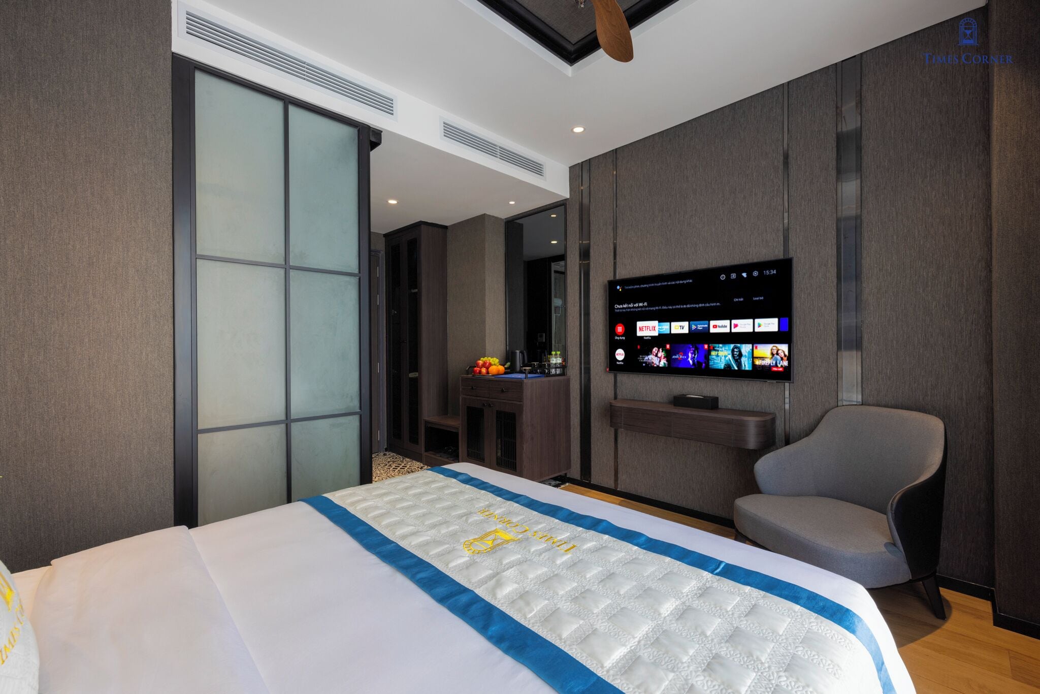 Una habitación de hotel moderna con una cama grande, un televisor de pantalla plana montado en la pared, un escritorio con una silla y una puerta corredera que da al baño.