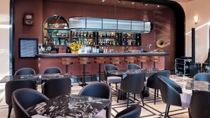 A bar area with a curved counter, multiple stools, and a variety of bottles. - Times Corner Amalfi Hotel (Phu Quoc)