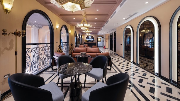 A hotel corridor with arched windows, a seating area with sofas and chairs, and decorative lighting fixtures. - Times Corner Amalfi Hotel (Phu Quoc)