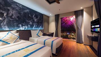 Camera d'albergo con due letti, un quadro grande appeso al muro, una televisione e un balcone con vista sui fuochi d'artificio.