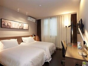 Habitación de hotel con dos camas, un escritorio, una silla, un televisor y un cuadro en la pared.