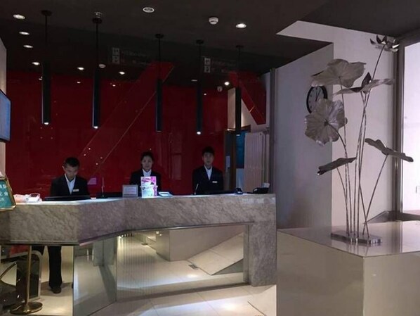 Un mostrador de recepción con tres empleados, un diseño interior moderno y una planta decorativa.