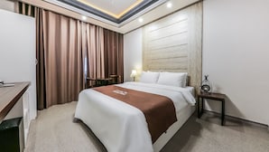 A hotel room with a large bed, a desk, a lamp, and a nightstand. - hotel gyeryong (Gyeryong)