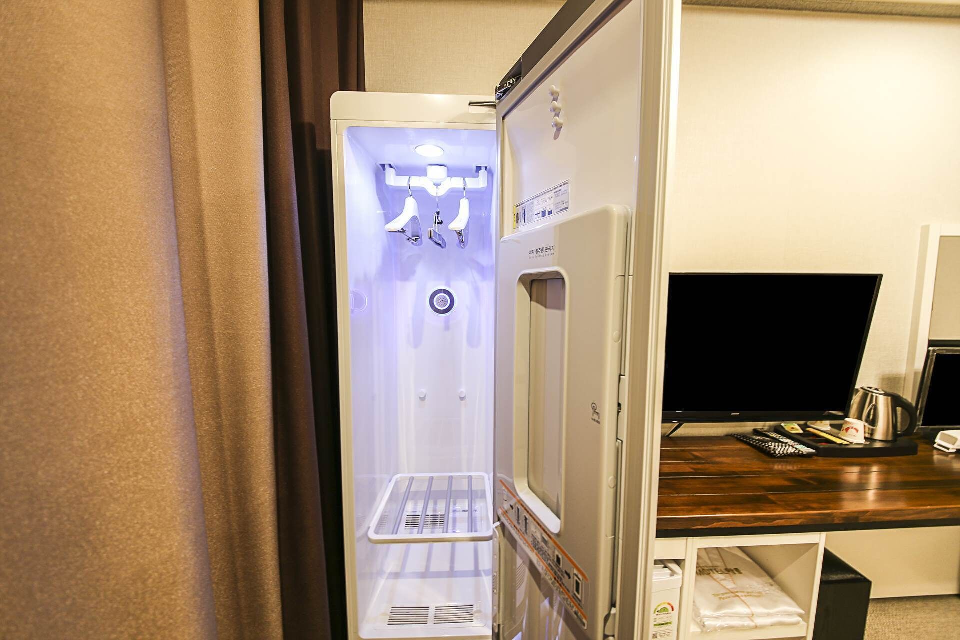 Una camera d'albergo con un minibar, una televisione e una scrivania con una macchina del caffè.