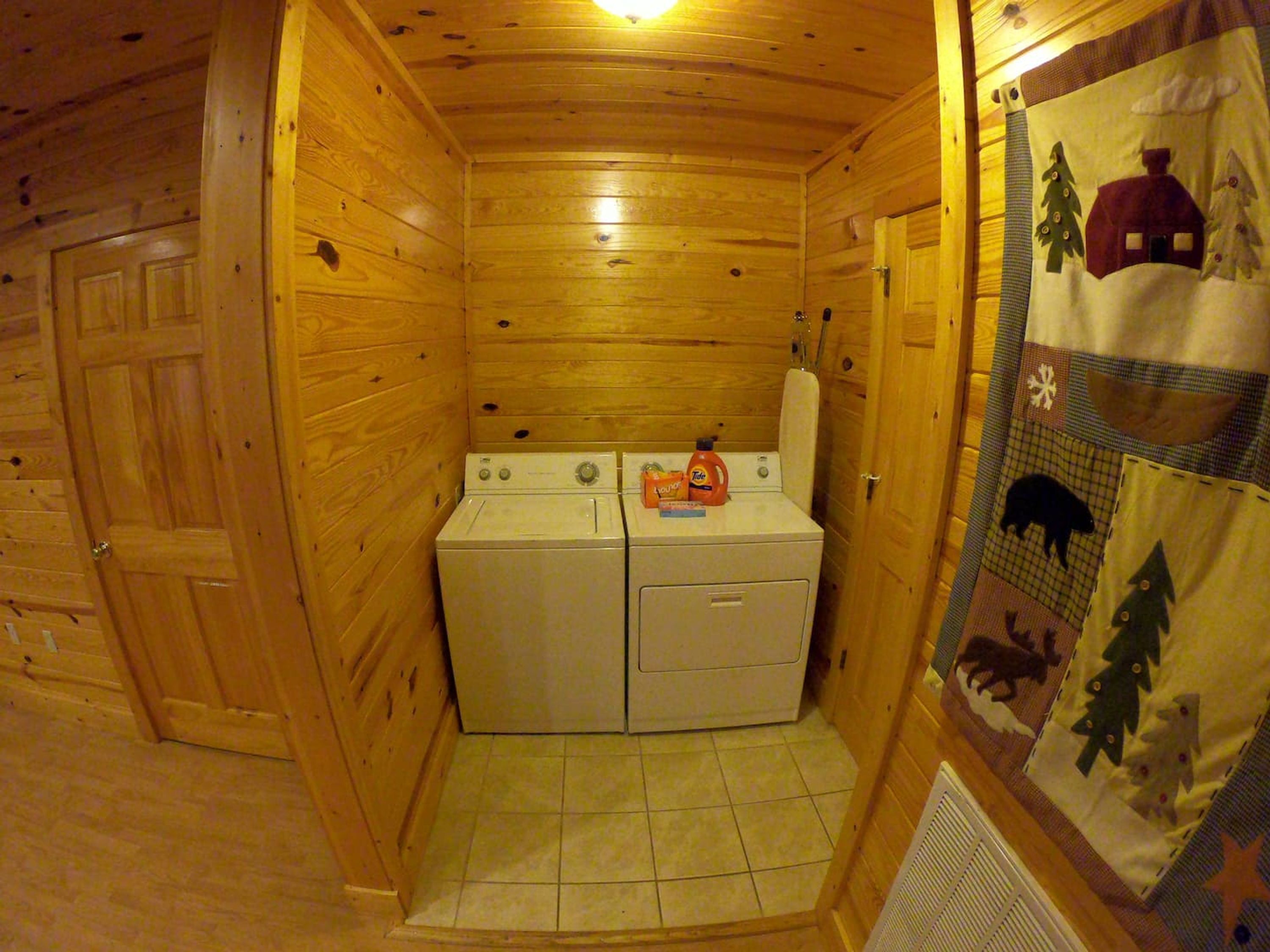 A compact laundry room with two stacked washing machines, a drying rack, and a door with a wooden frame.