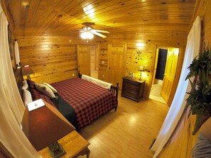 A wooden cabin bedroom with a bed, dresser, and ceiling fan. - Beautiful Cabin w hot tub Sauna Pool Table (Sevierville)