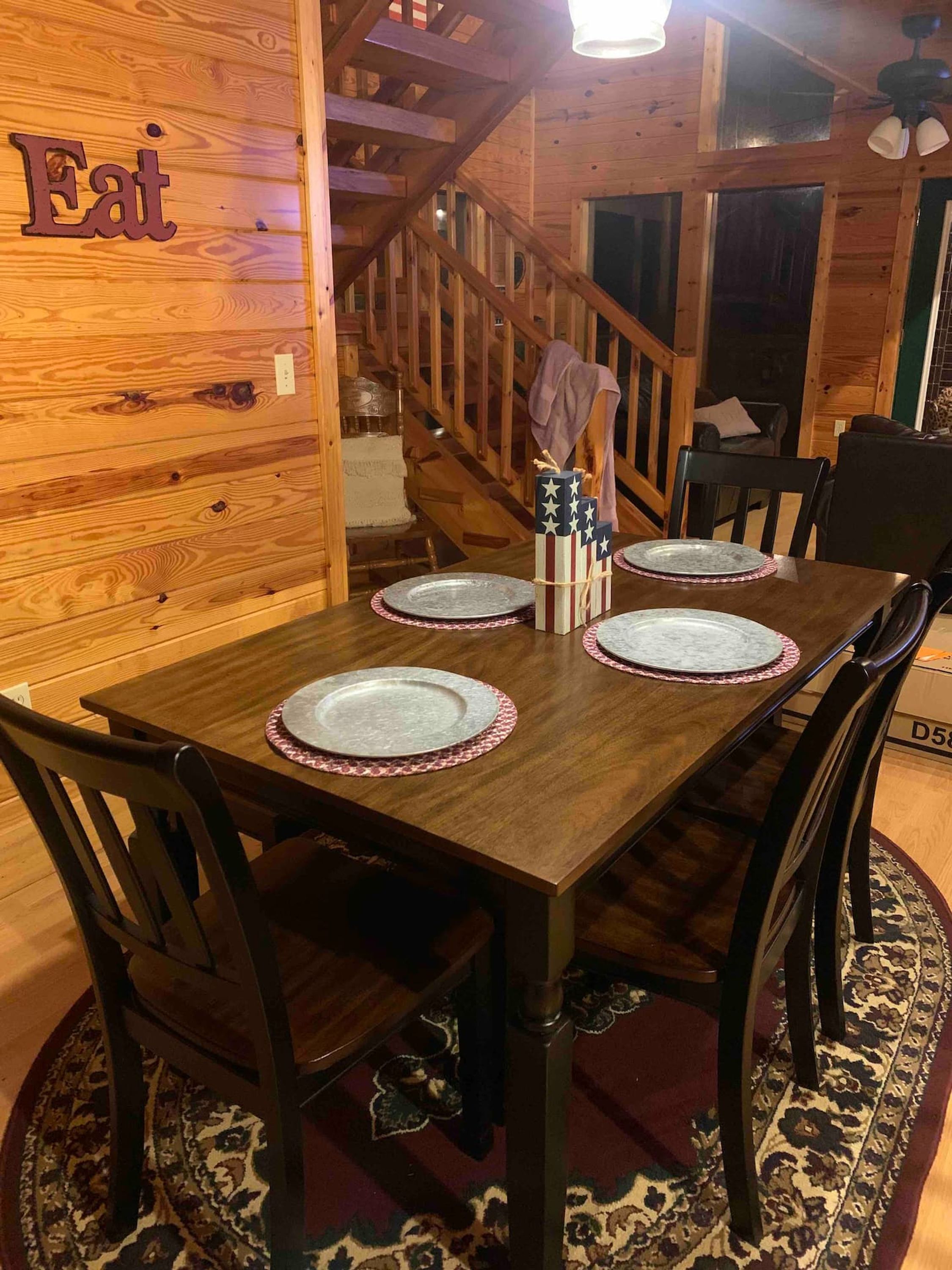 A wooden dining table set with plates and a gift box, surrounded by chairs.