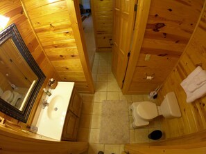 A wooden cabin bathroom with a sink, toilet, and mirror. - Beautiful Cabin w hot tub Sauna Pool Table (Sevierville)