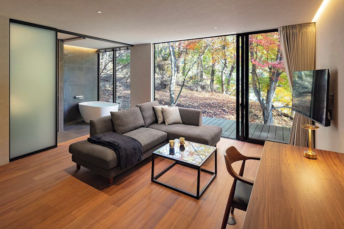 A modern living room with a sectional sofa, a glass coffee table, and a TV.