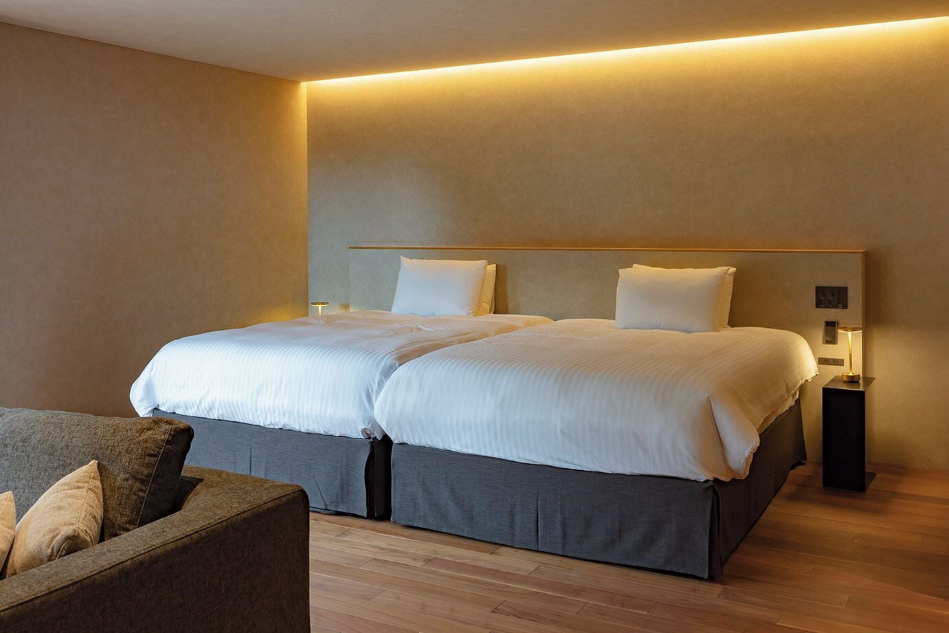 Une chambre d’hôtel moderne avec un grand lit, deux tables de chevet et un canapé.