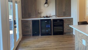 Een keuken met houten kasten, een wijnkoeler en een opgehangen gewei.