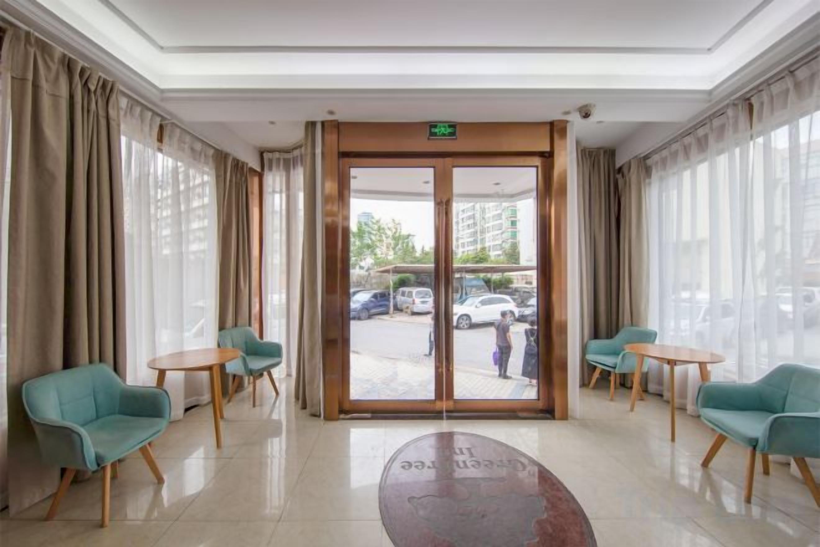 A hotel lobby with a reception desk, two round tables, and four chairs.