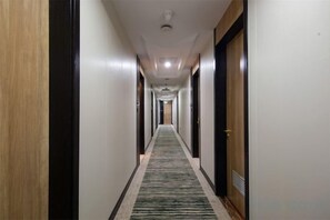 A hotel corridor with a carpeted floor, doors on both sides, and a ceiling light fixture. - GreenTree Smart Choice Hotel (Shanghai Chest hospital Hongqiao Road Metro Station) (Shanghai)