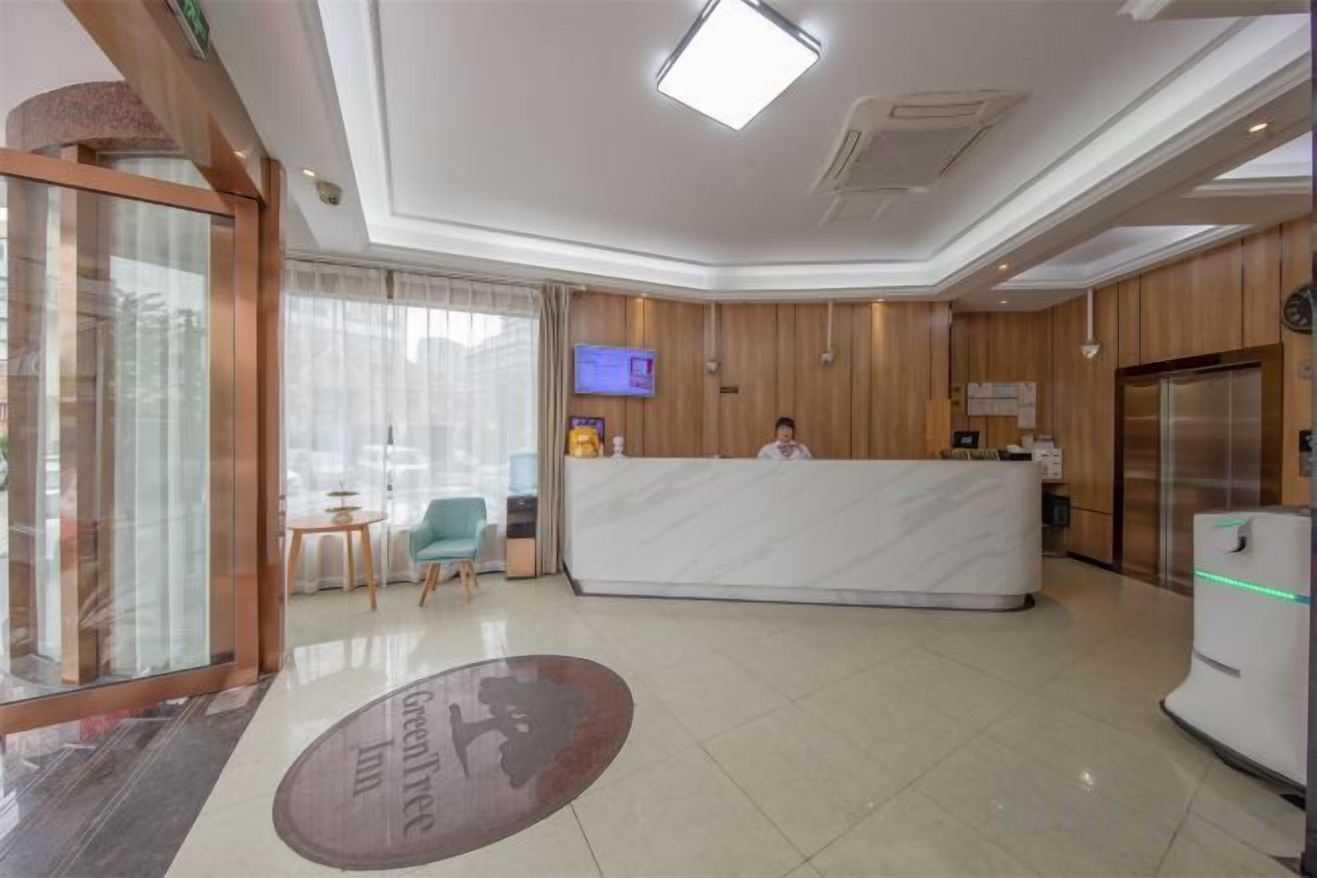 Uma área de recepção de hotel com balcão de mármore, televisão e frigorífico.