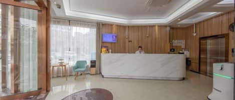 Et hotellets receptionsområde med en marmor disk, et fjernsyn og et køleskab.