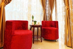 A room with two red upholstered chairs, a small round table with a plant, and curtains. - GreenTree Smart Choice Hotel (Shanghai Chest hospital Hongqiao Road Metro Station) (Shanghai)