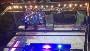 A pool area with a blue-lit water feature and a seating area with string lights.