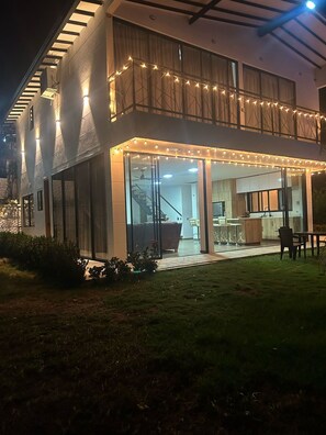 A modern two-story house with a glass entrance, outdoor seating, and string lights. - Los Pinos Farm, Sopetran, Antioquia (Antioquia)