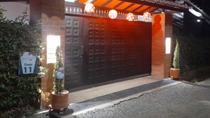 A gated entrance with a large, dark brown garage door, a small potted plant, and a sign indicating room number 11.