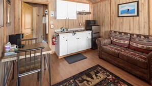 A compact, wood-paneled room with a kitchenette, a sofa, and a dining area.