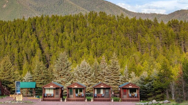 A row of wooden cabins with a mountain backdrop.