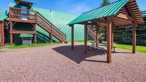 A building with a green metal roof, wooden stairs, and a covered picnic area. - Wolf Cabin! 6 miles to Glacier! (Coram)