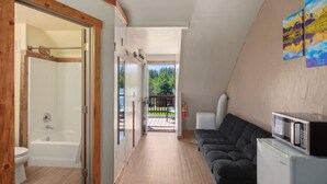 Un espacio habitable compacto con ducha, sofá y microondas.