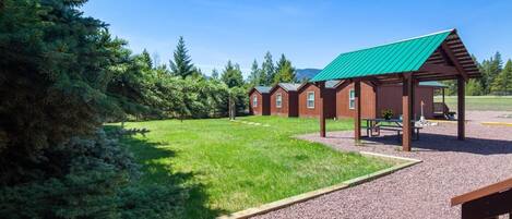 Un chalet doté de plusieurs cabanes, d’un espace pique-nique couvert et d’une pelouse bien entretenue.