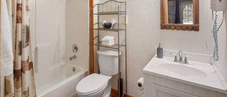 A bathroom with a bathtub, toilet, and a sink with a mirror above.