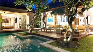 A poolside area with a bed, lounge chairs, and a TV. - Villa Pacha Seminyak (Seminyak)