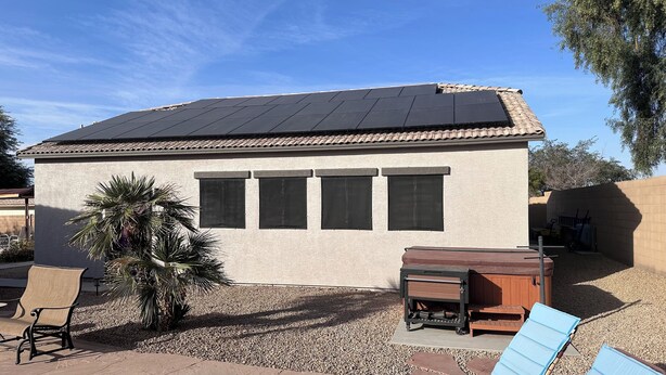 A small building with a tiled roof, four windows, and a patio area with a chair and a table. - Cozy Guest House Apartment w/ Shared Backyard Oasis, Spa & Pool (Litchfield Park)