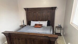 A bedroom with a large wooden bed, a bedside table, and a nightstand. - Cozy Guest House Apartment w/ Shared Backyard Oasis, Spa & Pool (Litchfield Park)