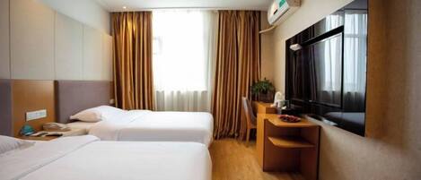 A hotel room with two beds, a desk, and a large window with curtains.