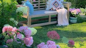 A wooden bench with cushions and a blanket, surrounded by lush greenery and pink hydrangea flowers. - GreenTree Inn Jiangsu Wuxi Jiangyin Yunting Changshan Avenue Chengyang Road Business Hotel (Jiangyin)