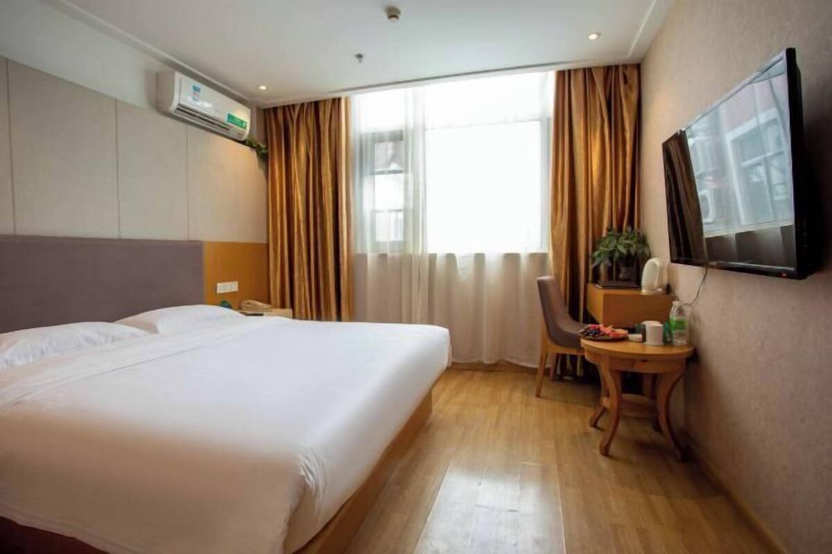 Et hotelværelse med seng, skrivebord, stol, fjernsyn og aircondition.